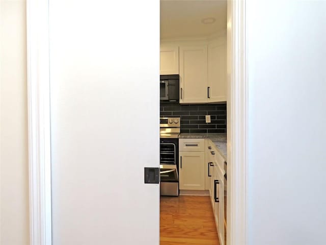 kitchen with white cabinets, light wood-type flooring, electric range, and decorative backsplash