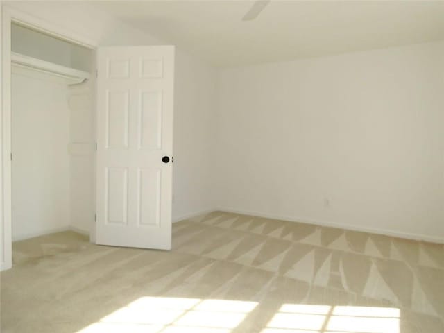 unfurnished bedroom featuring ceiling fan, light colored carpet, and a closet