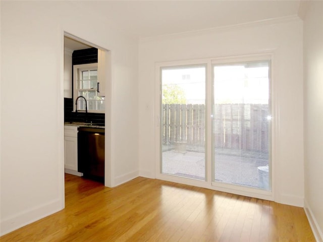 unfurnished room featuring light hardwood / wood-style flooring, crown molding, and sink