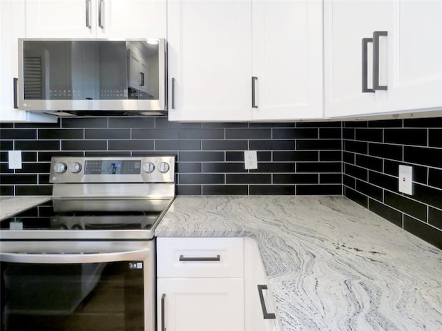 kitchen with backsplash, light stone counters, white cabinets, and stainless steel appliances