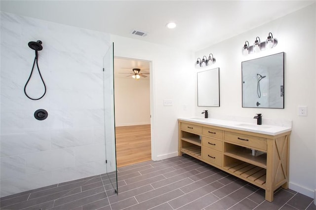 bathroom with double vanity, a sink, wood finished floors, baseboards, and walk in shower