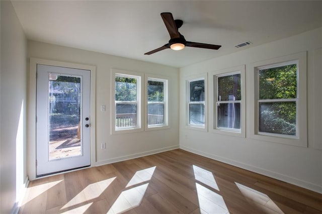 unfurnished sunroom featuring visible vents and ceiling fan