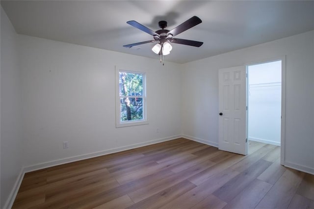 empty room with ceiling fan, baseboards, and wood finished floors