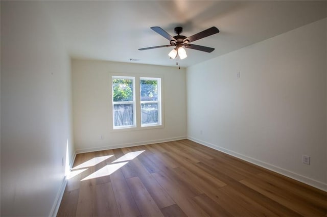 unfurnished room featuring baseboards, visible vents, ceiling fan, and wood finished floors