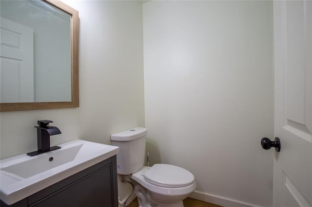 bathroom with toilet, baseboards, and vanity