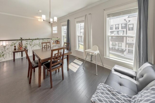 dining area with ornamental molding, dark wood-type flooring, sink, and a notable chandelier