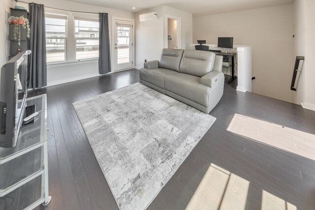 living room featuring dark hardwood / wood-style flooring and a wall mounted air conditioner