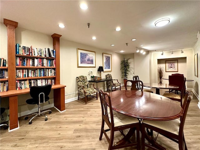 dining area with track lighting and light hardwood / wood-style flooring