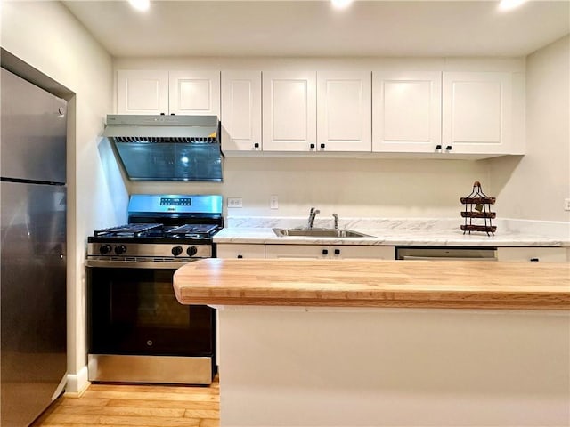 kitchen featuring white cabinetry, wood counters, stainless steel appliances, and sink