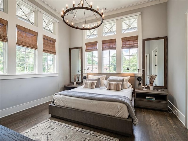 bedroom with dark hardwood / wood-style floors, a chandelier, multiple windows, and ornamental molding