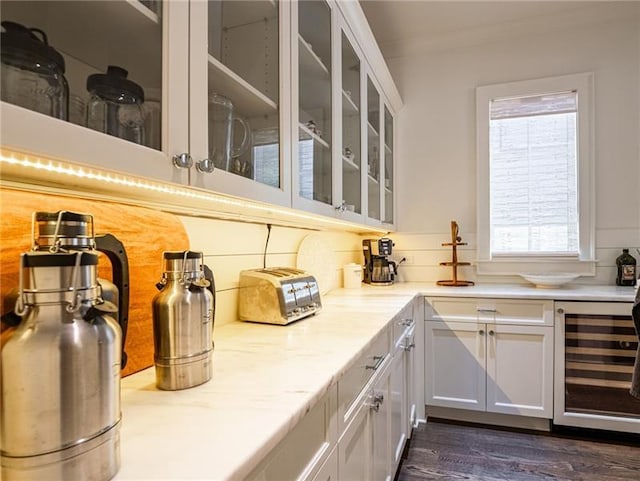 kitchen with tasteful backsplash, beverage cooler, light stone counters, white cabinets, and dark wood-type flooring