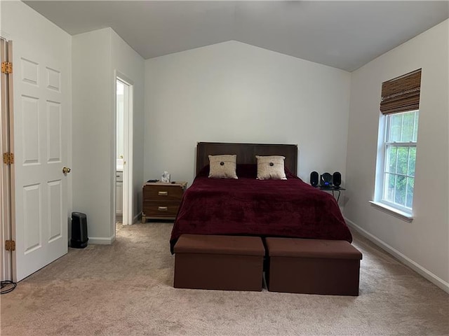 carpeted bedroom with vaulted ceiling and ensuite bathroom