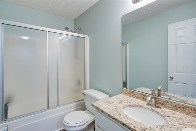 bathroom featuring toilet, bath / shower combo with glass door, a textured ceiling, and vanity