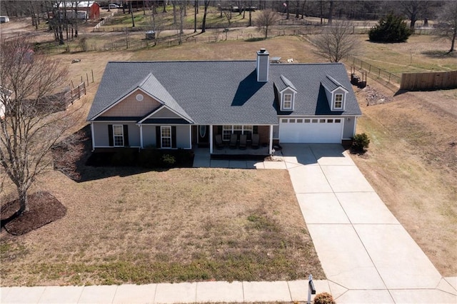 view of front facade with a porch, driveway, a front lawn, and fence