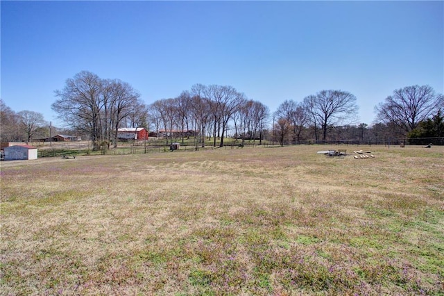 view of yard with fence and a rural view