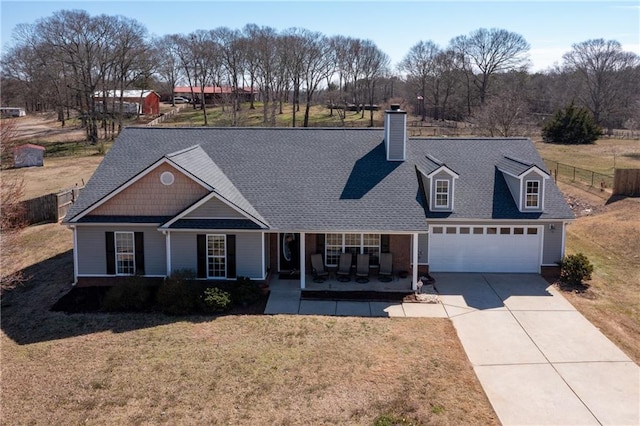 view of front of home featuring a porch, concrete driveway, fence, a garage, and a front lawn