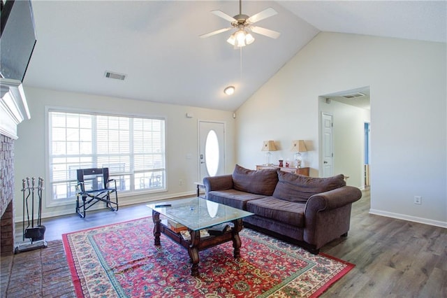 living area with high vaulted ceiling, visible vents, ceiling fan, and wood finished floors