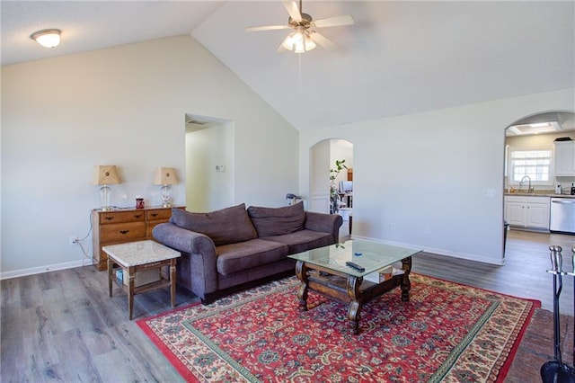 living room featuring arched walkways, high vaulted ceiling, wood finished floors, a ceiling fan, and baseboards