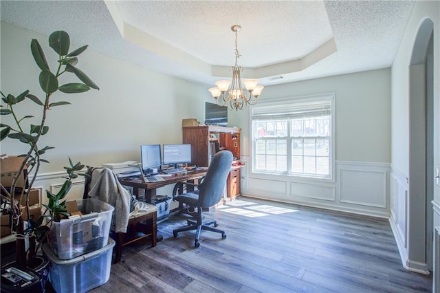 office space featuring a tray ceiling, wainscoting, a textured ceiling, and wood finished floors