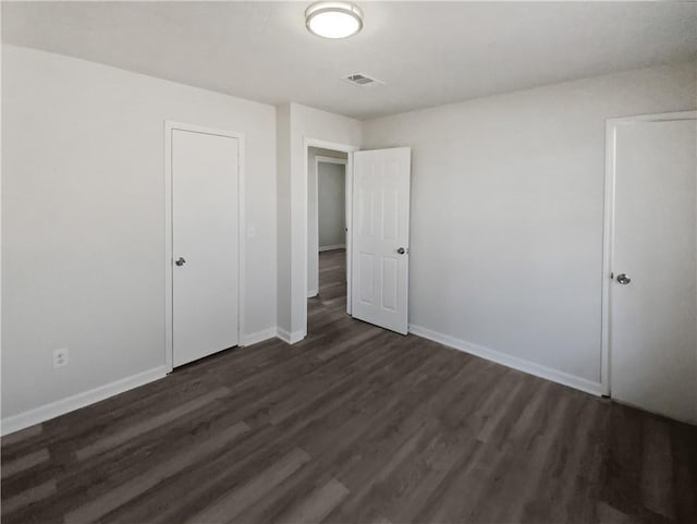 unfurnished bedroom with dark wood-type flooring and a closet