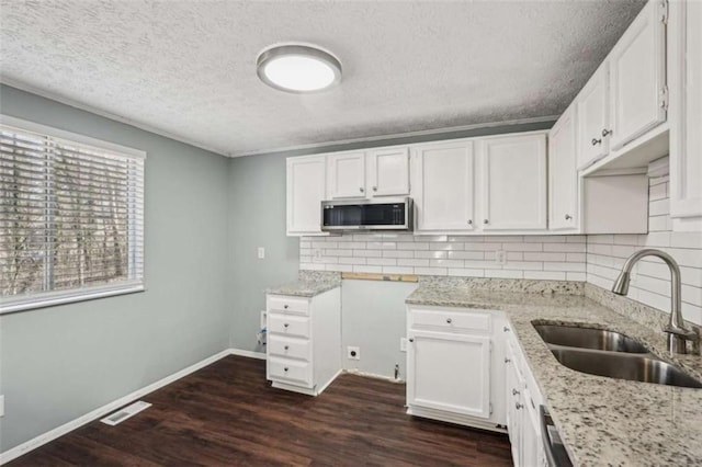 kitchen featuring sink, white cabinets, backsplash, light stone countertops, and dark wood-type flooring