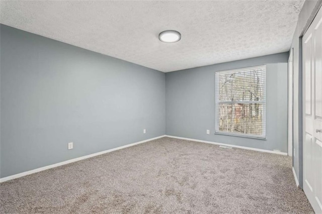 carpeted empty room with a textured ceiling