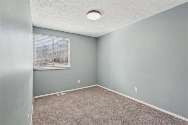 carpeted empty room featuring a textured ceiling