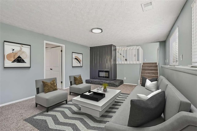 living room featuring light colored carpet, a large fireplace, and a textured ceiling