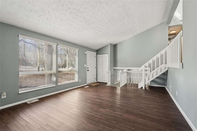 unfurnished living room with vaulted ceiling, dark hardwood / wood-style floors, and a textured ceiling