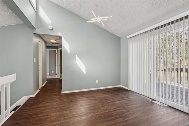 empty room with vaulted ceiling, a textured ceiling, and dark hardwood / wood-style flooring