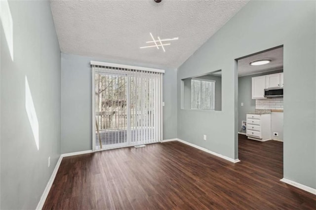 spare room with lofted ceiling, dark hardwood / wood-style flooring, and a textured ceiling