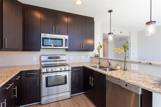 kitchen with stainless steel appliances, sink, backsplash, light wood-type flooring, and pendant lighting