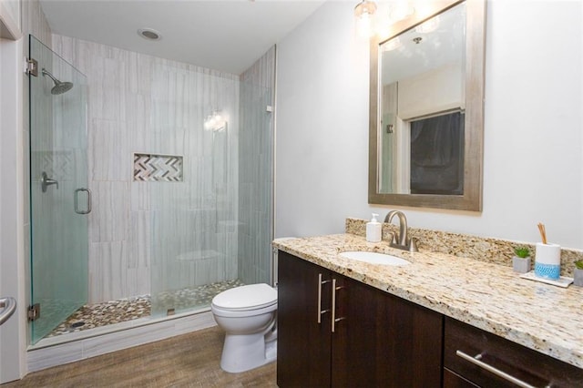 bathroom with hardwood / wood-style floors, an enclosed shower, vanity, and toilet