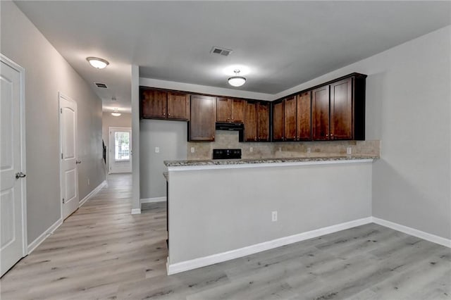 kitchen featuring tasteful backsplash, kitchen peninsula, light stone countertops, light hardwood / wood-style flooring, and dark brown cabinetry