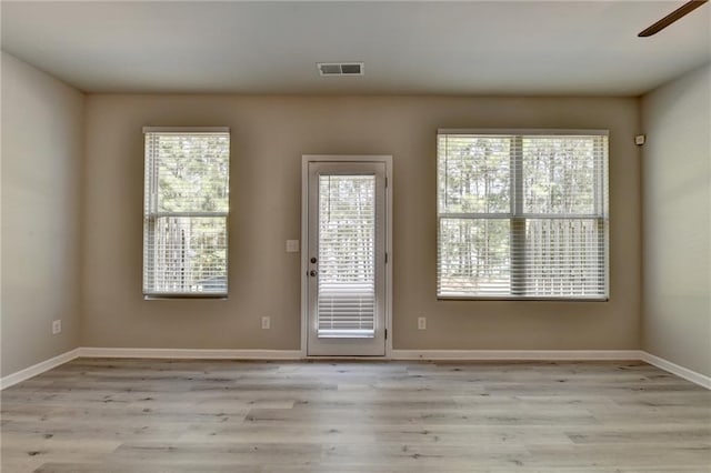 empty room featuring ceiling fan, light wood-type flooring, and plenty of natural light