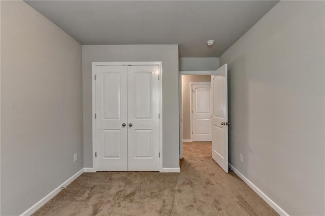 unfurnished bedroom with a closet and light colored carpet