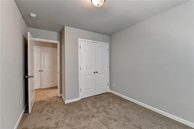 unfurnished bedroom with a closet and light colored carpet