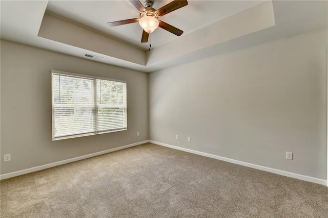 carpeted spare room featuring ceiling fan and a tray ceiling