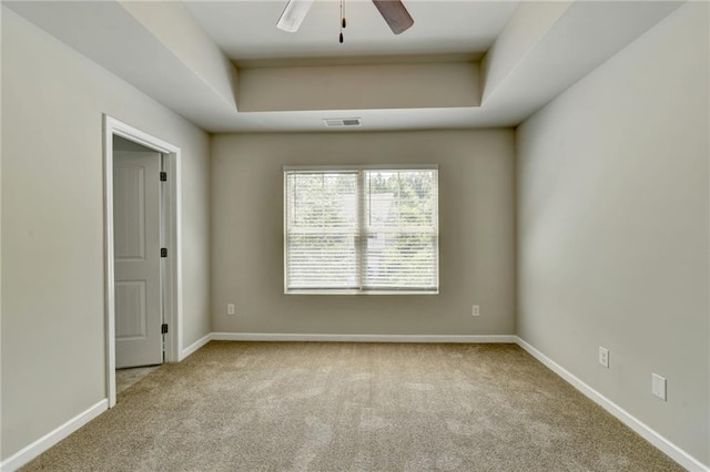 unfurnished room featuring ceiling fan, a raised ceiling, and light colored carpet