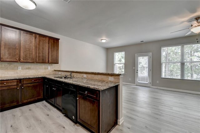 kitchen with light hardwood / wood-style flooring, light stone counters, ceiling fan, kitchen peninsula, and sink