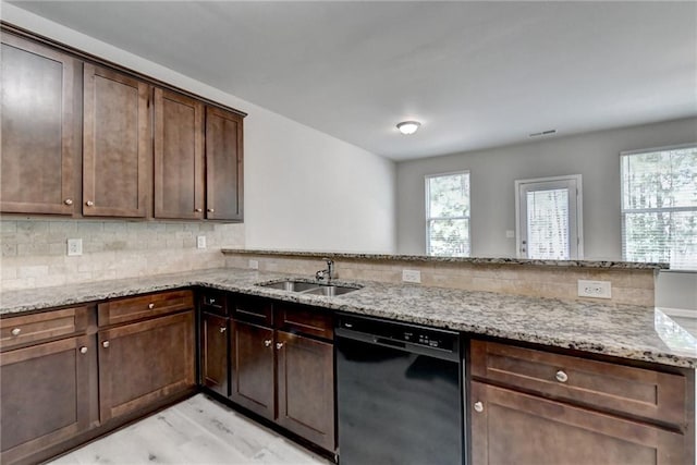 kitchen with black dishwasher, light stone countertops, light wood-type flooring, sink, and kitchen peninsula