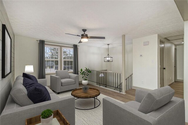 empty room with a textured ceiling, ceiling fan, wood finished floors, and baseboards