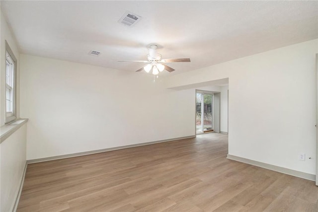 empty room featuring light wood-style floors, visible vents, baseboards, and a ceiling fan