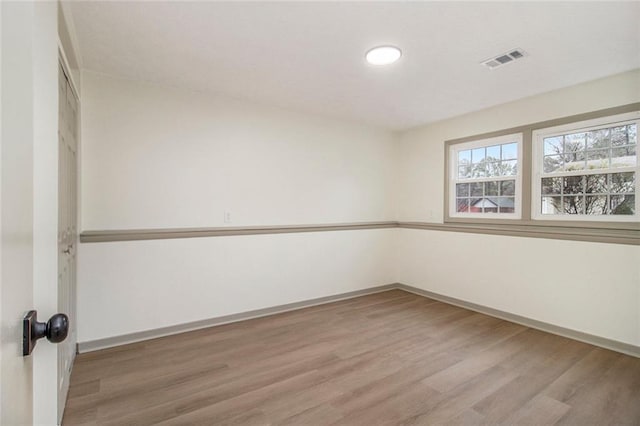 spare room with baseboards, visible vents, and wood finished floors