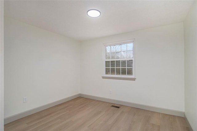 spare room featuring light wood-style flooring, visible vents, and baseboards