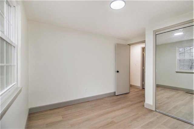 unfurnished bedroom with a closet, visible vents, light wood-style flooring, and baseboards