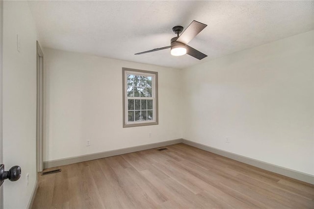 spare room with light wood finished floors, visible vents, baseboards, and a textured ceiling