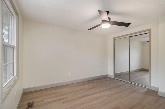 unfurnished bedroom featuring a closet, visible vents, light wood-style flooring, and baseboards