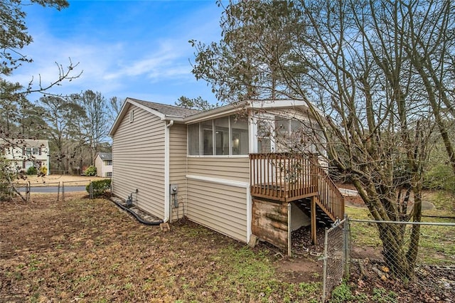 view of side of home featuring fence, a sunroom, stairway, a wooden deck, and a gate