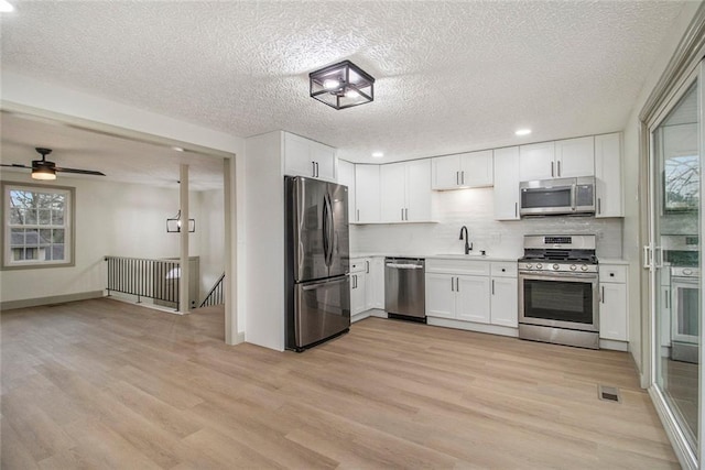 kitchen featuring stainless steel appliances, light countertops, visible vents, a sink, and light wood-type flooring